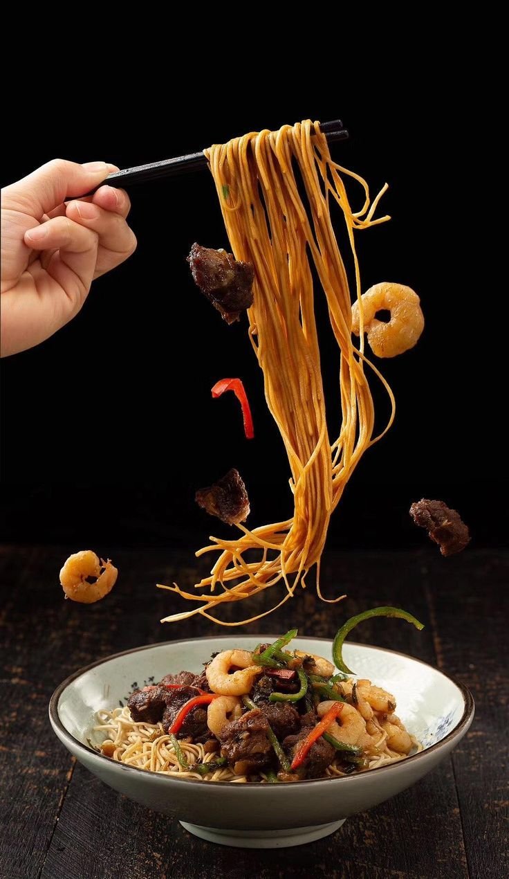 Noodles lifted high with chopsticks